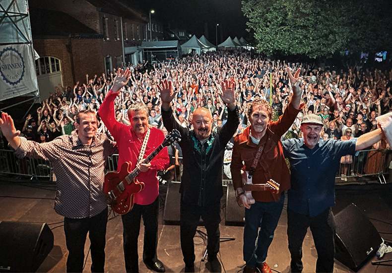 The band, The Fabulous Thunderbirds, on stage with the audience in the background.